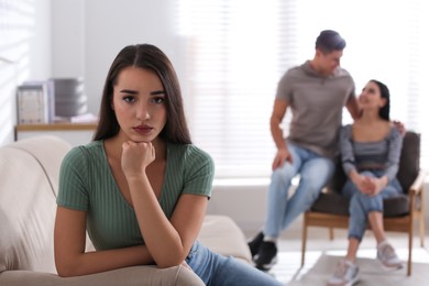 Photo of Unhappy woman feeling jealous while couple spending time together at home