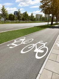Photo of Bicycle lane with white signs painted on asphalt in city