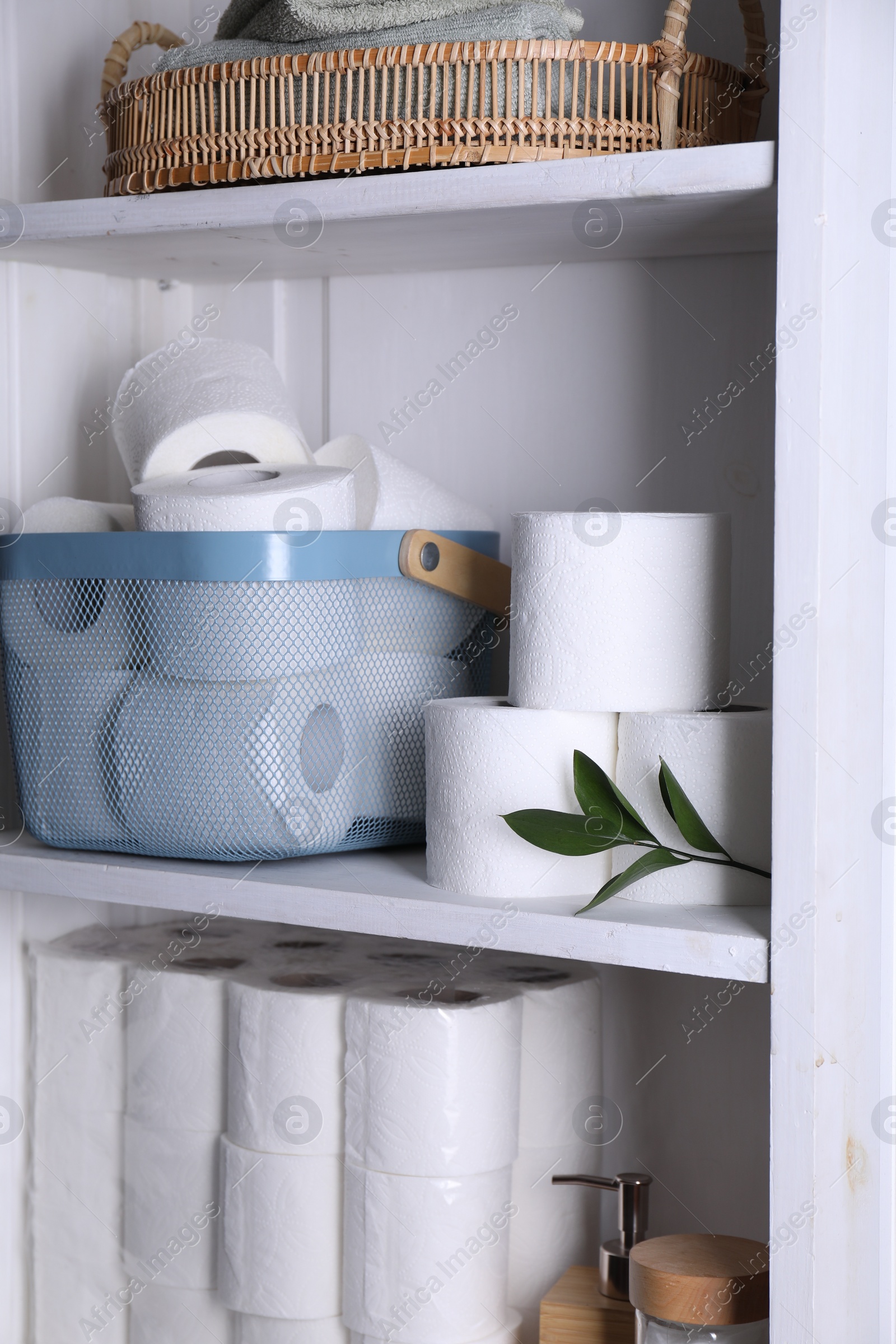 Photo of Toilet paper rolls and green leaves on white shelves