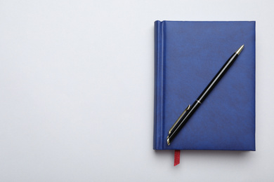 Stylish blue notebook and pen on light grey background, top view. Space for text