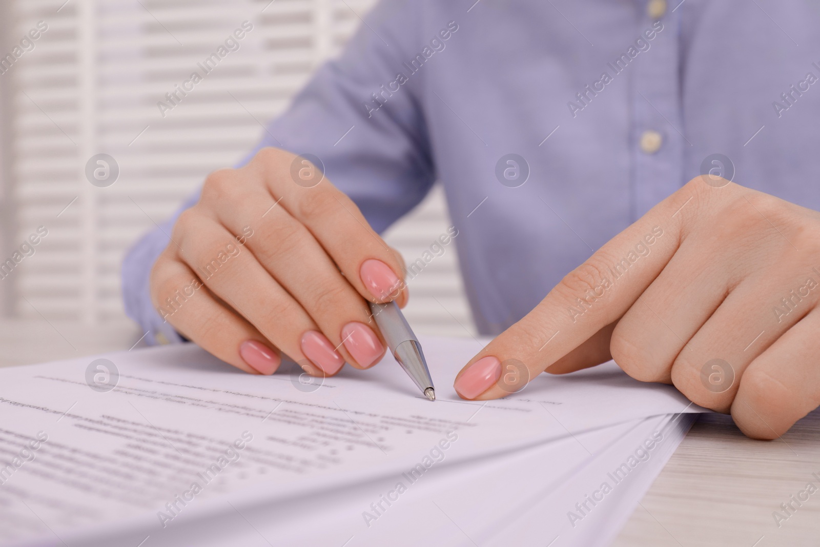 Photo of Woman signing document at wooden table, closeup