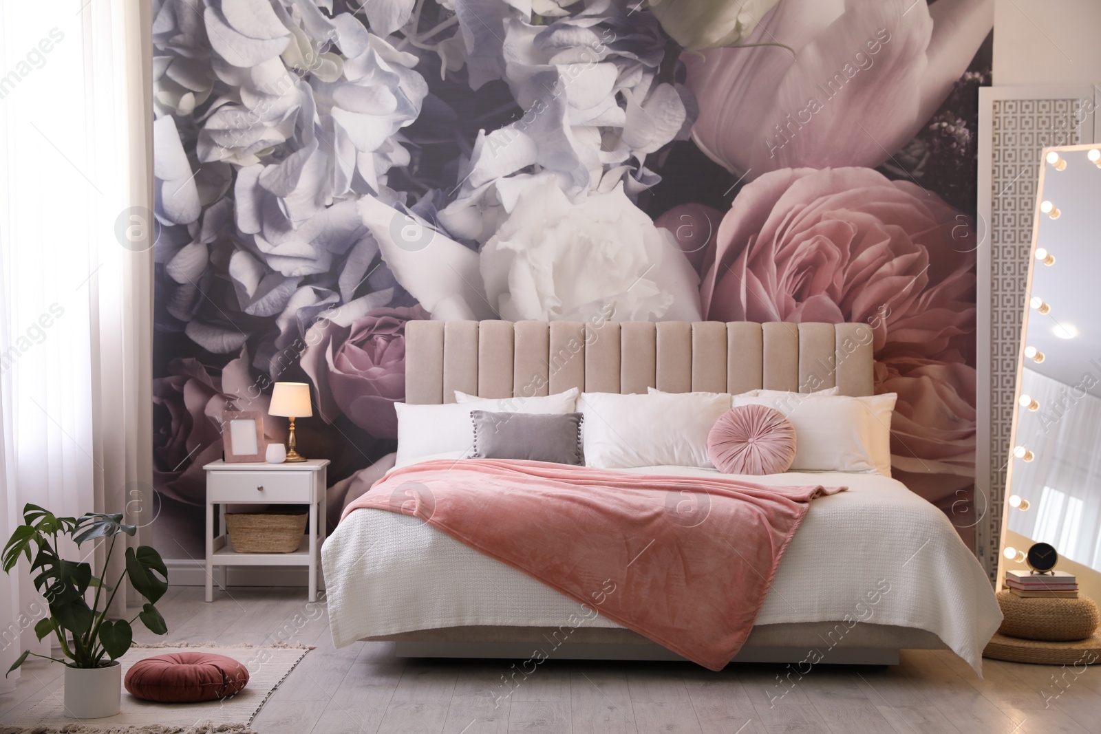 Photo of Beautiful room interior with large bed, mirror and floral pattern on wall