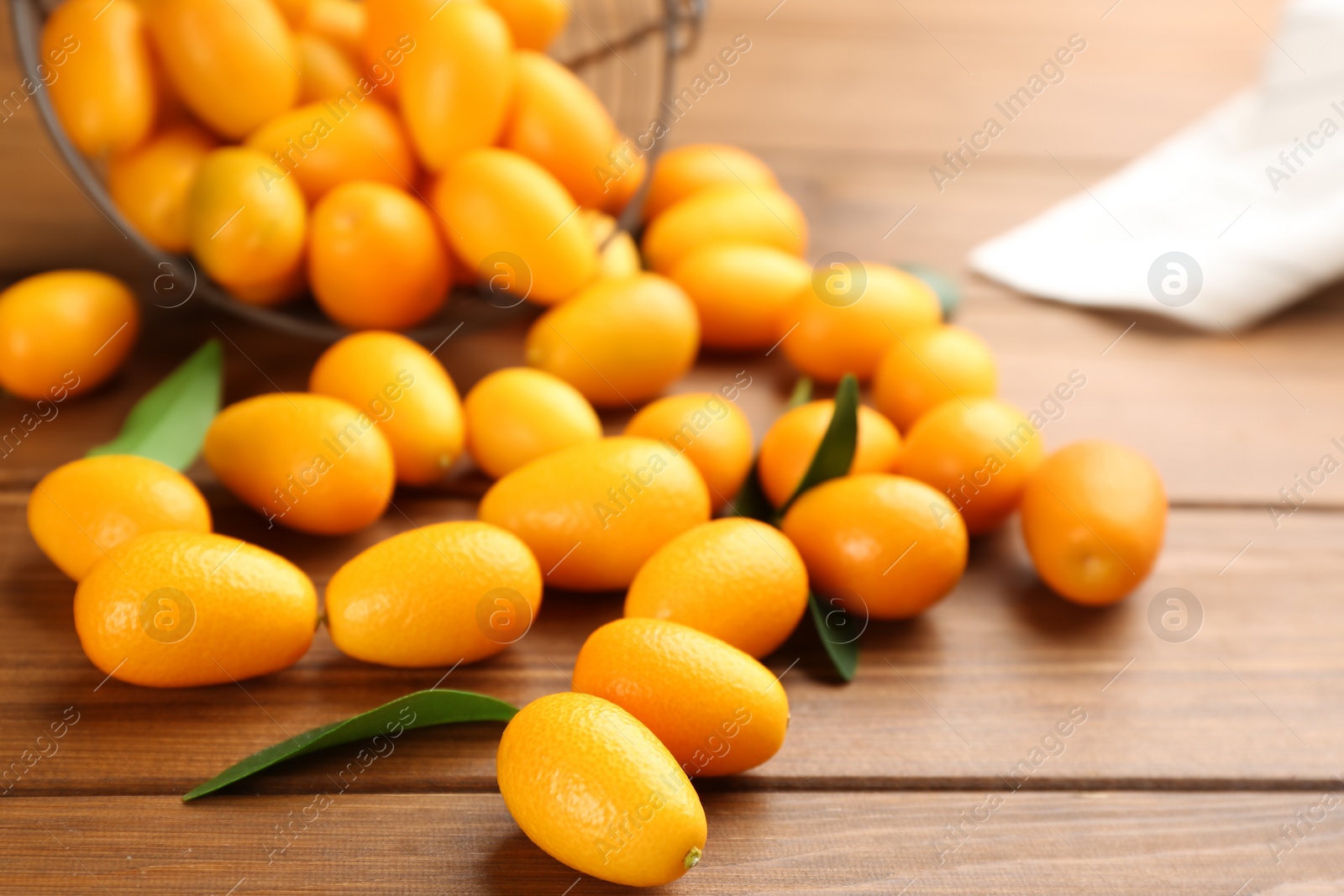 Photo of Fresh ripe kumquats with green leaves on wooden table