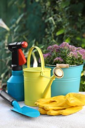 Photo of Watering can, flowers and gardening tools on table outdoors
