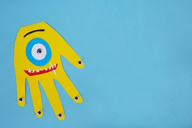 Funny yellow hand shaped monster on light blue background, top view with space for text. Halloween decoration