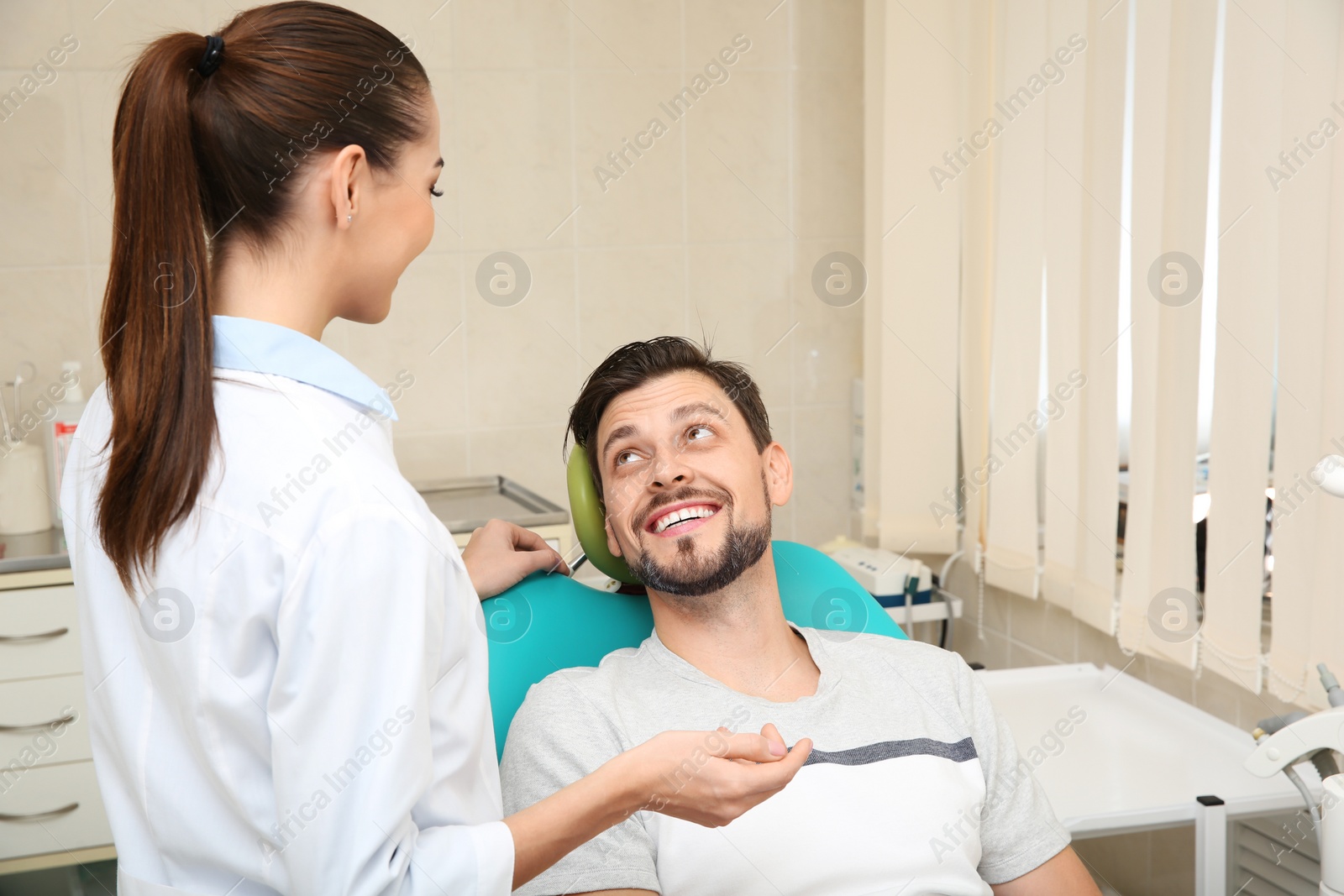 Photo of Professional dentist working with patient in modern clinic