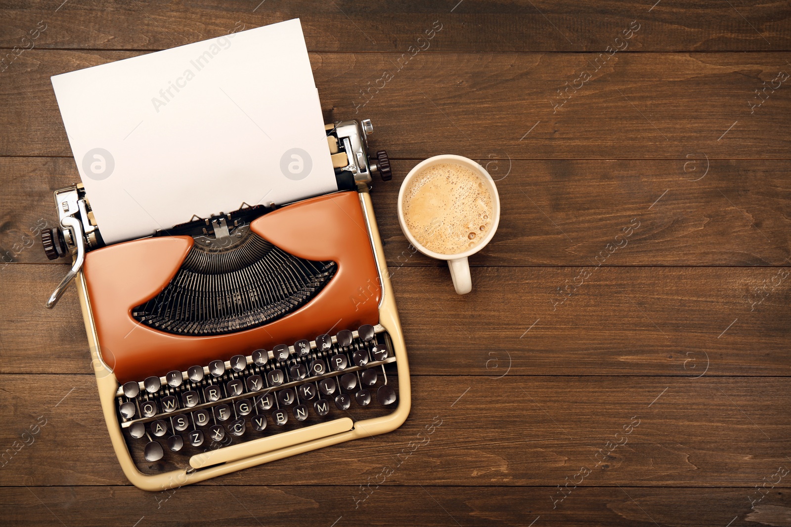 Photo of Vintage typewriter and cup of coffee on wooden table, flat lay. Space for text