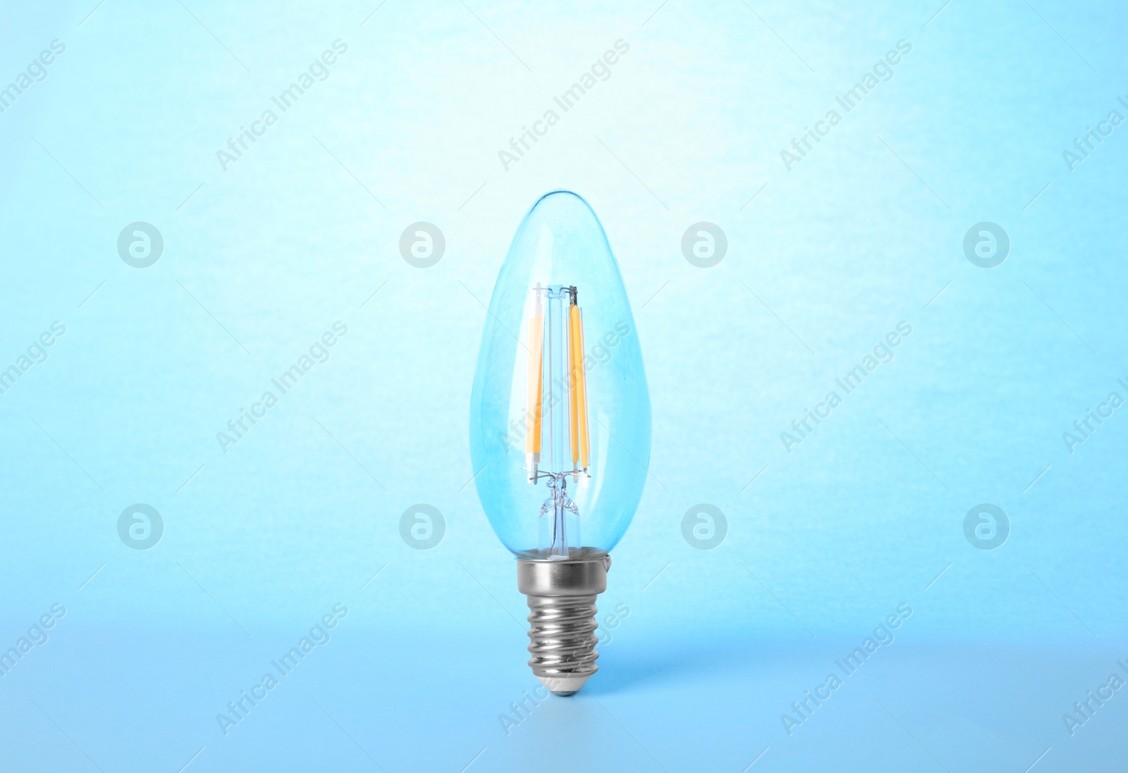 Photo of New modern lamp bulb on light blue background