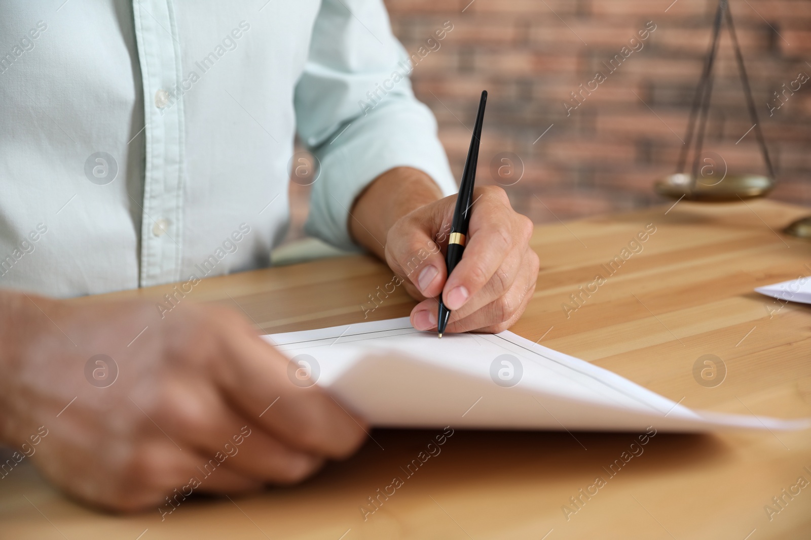 Photo of Male notary signing document at table in office, closeup