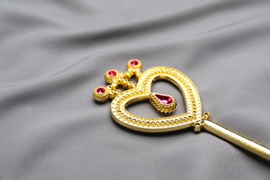 Photo of Beautiful golden magic wand on grey fabric, closeup