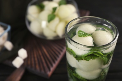 Photo of Glass with tasty melon ball drink on dark table, closeup