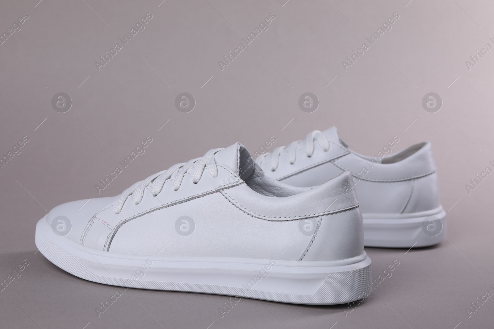 Photo of Pair of stylish white sneakers on grey background