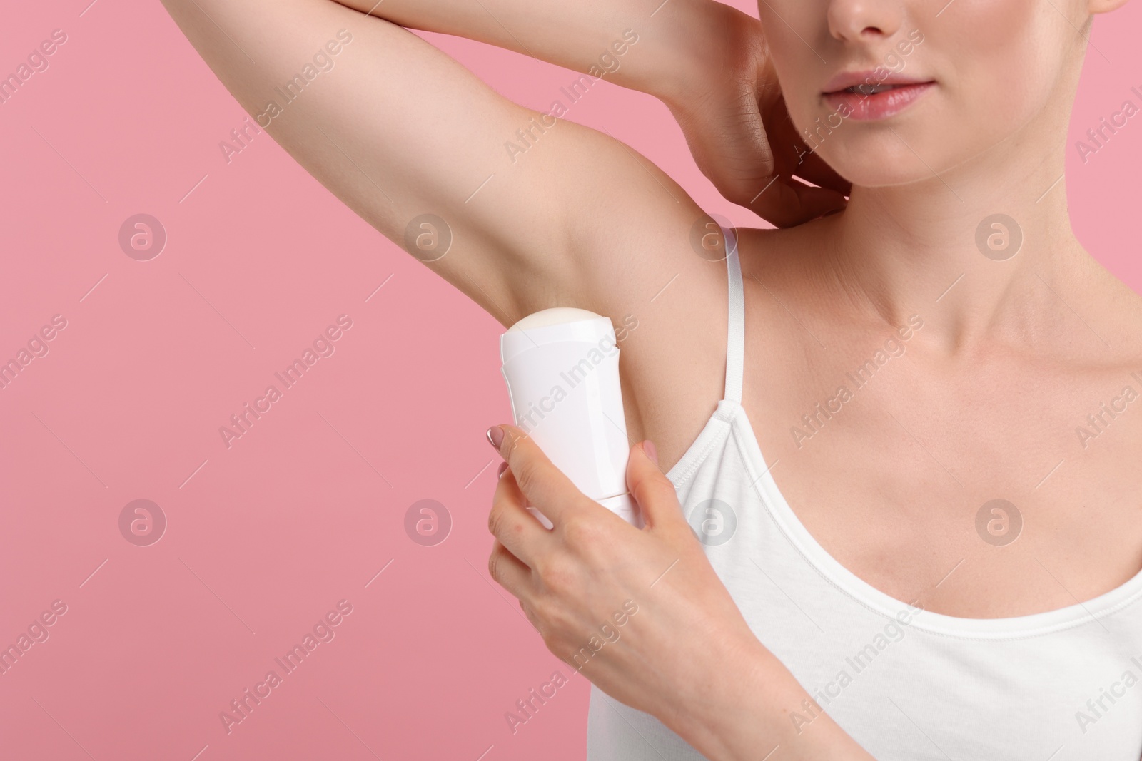 Photo of Woman applying deodorant on pink background, closeup. Space for text