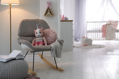 Photo of Cozy baby room interior with comfortable rocking chair