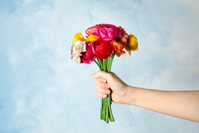 Photo of Woman holding bouquet with beautiful ranunculus flowers on color background