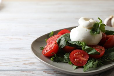Photo of Delicious burrata cheese served with tomatoes and basil on white wooden table, closeup. Space for text
