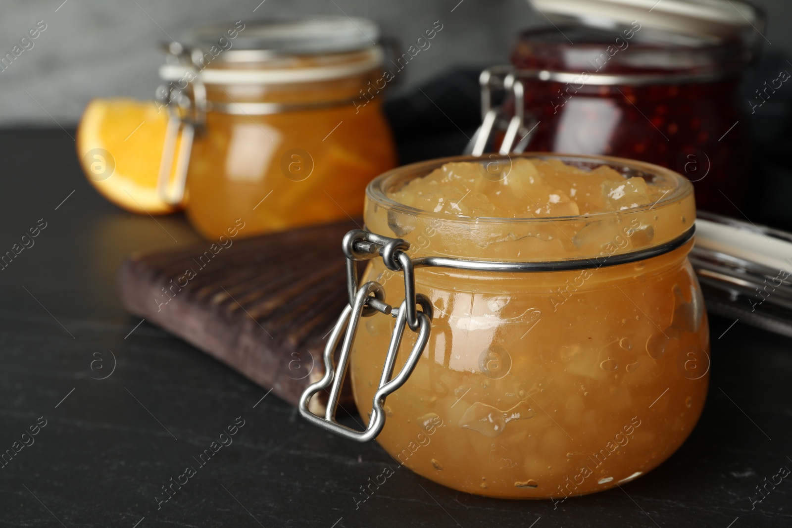 Photo of Delicious homemade jams on black wooden table