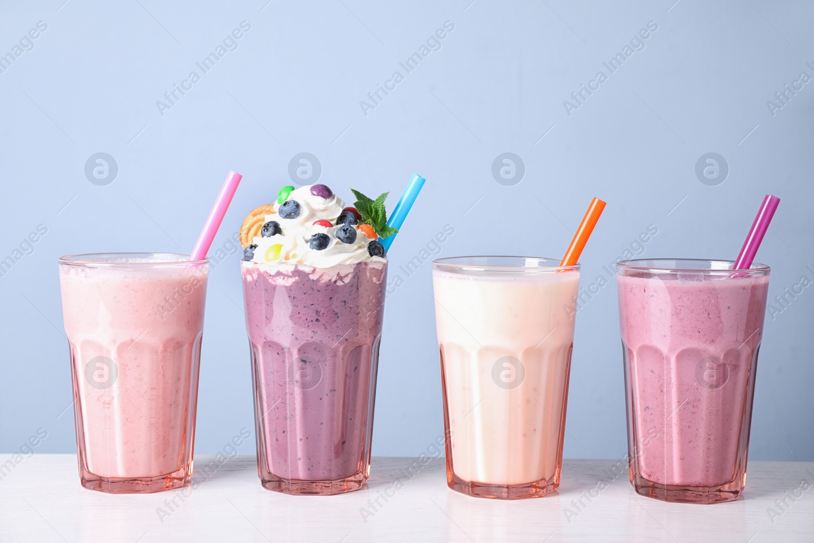 Photo of Different tasty milk shakes in glasses on white table