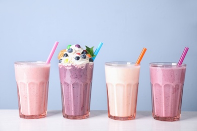 Different tasty milk shakes in glasses on white table