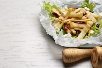 Delicious parsnip with lettuce, feta cheese and dates on white wooden table, closeup. Space for text