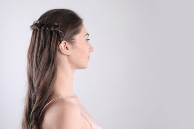 Woman with braided hair on light background. Space for text