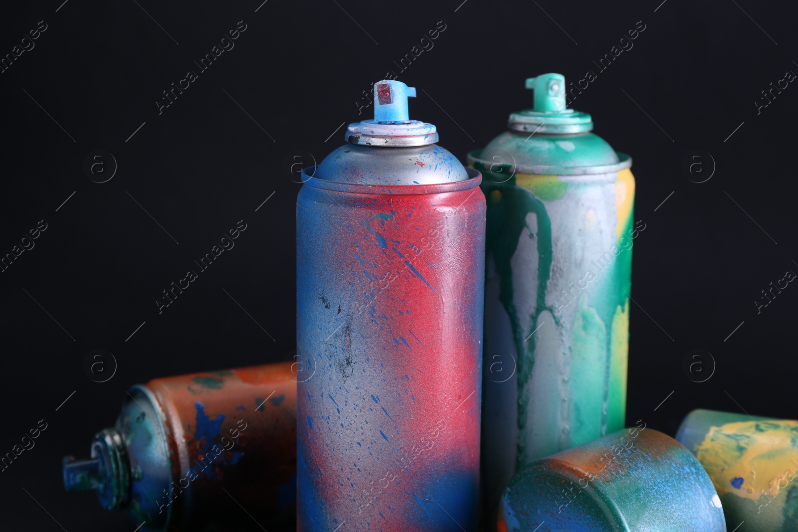 Photo of Many spray paint cans with caps on dark background