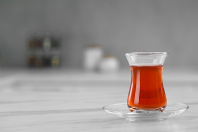 Glass of traditional Turkish tea on white marble table, space for text