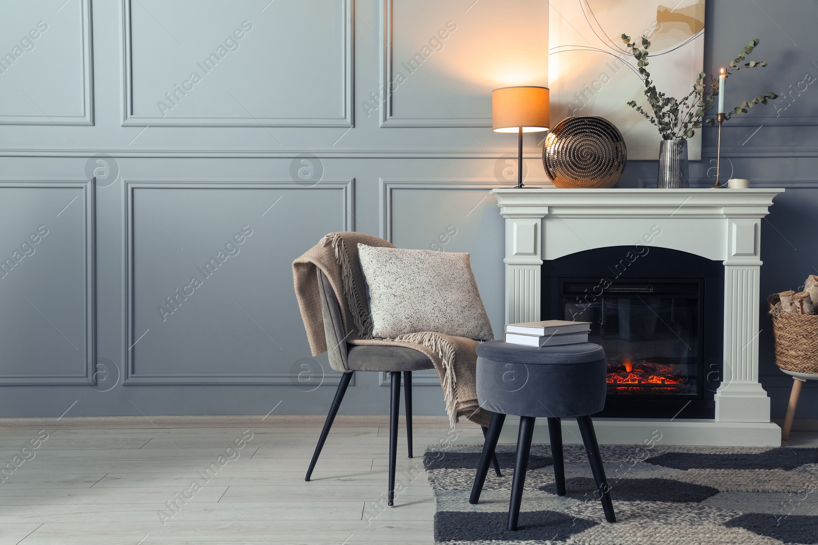 Photo of Beautiful fireplace, different decor and armchair in living room, space for text. Interior design