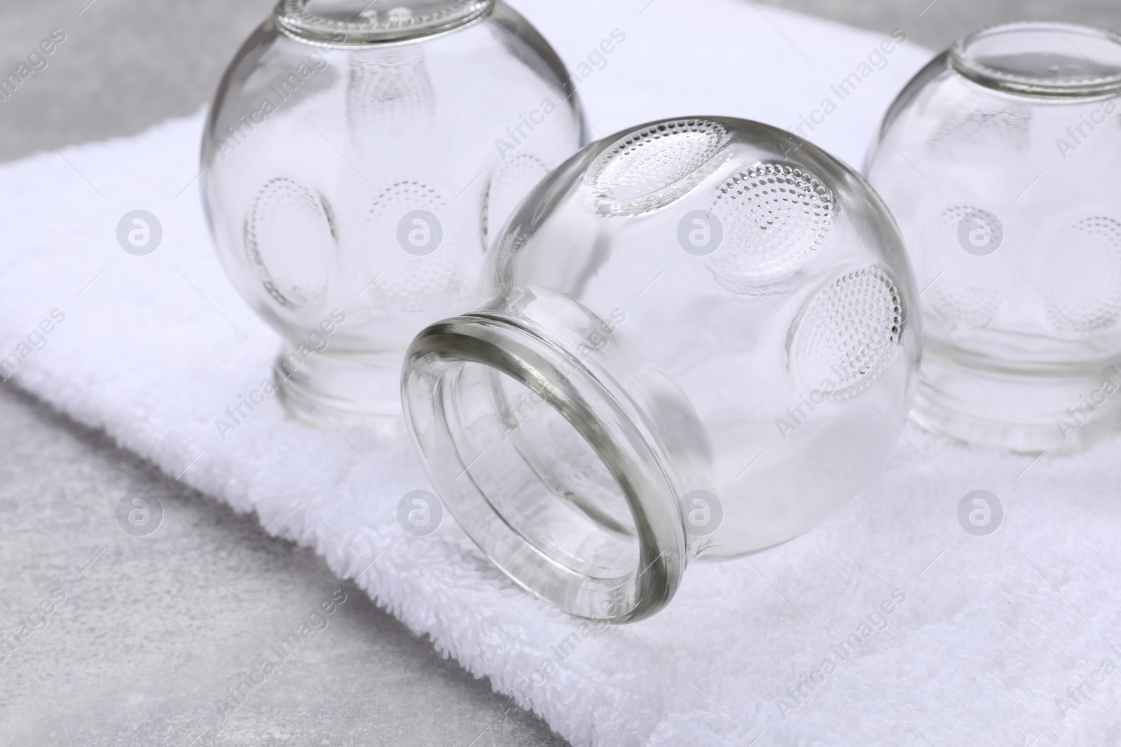 Photo of Glass cups and towel on grey table, closeup. Cupping therapy