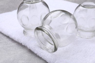 Photo of Glass cups and towel on grey table, closeup. Cupping therapy