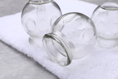 Glass cups and towel on grey table, closeup. Cupping therapy