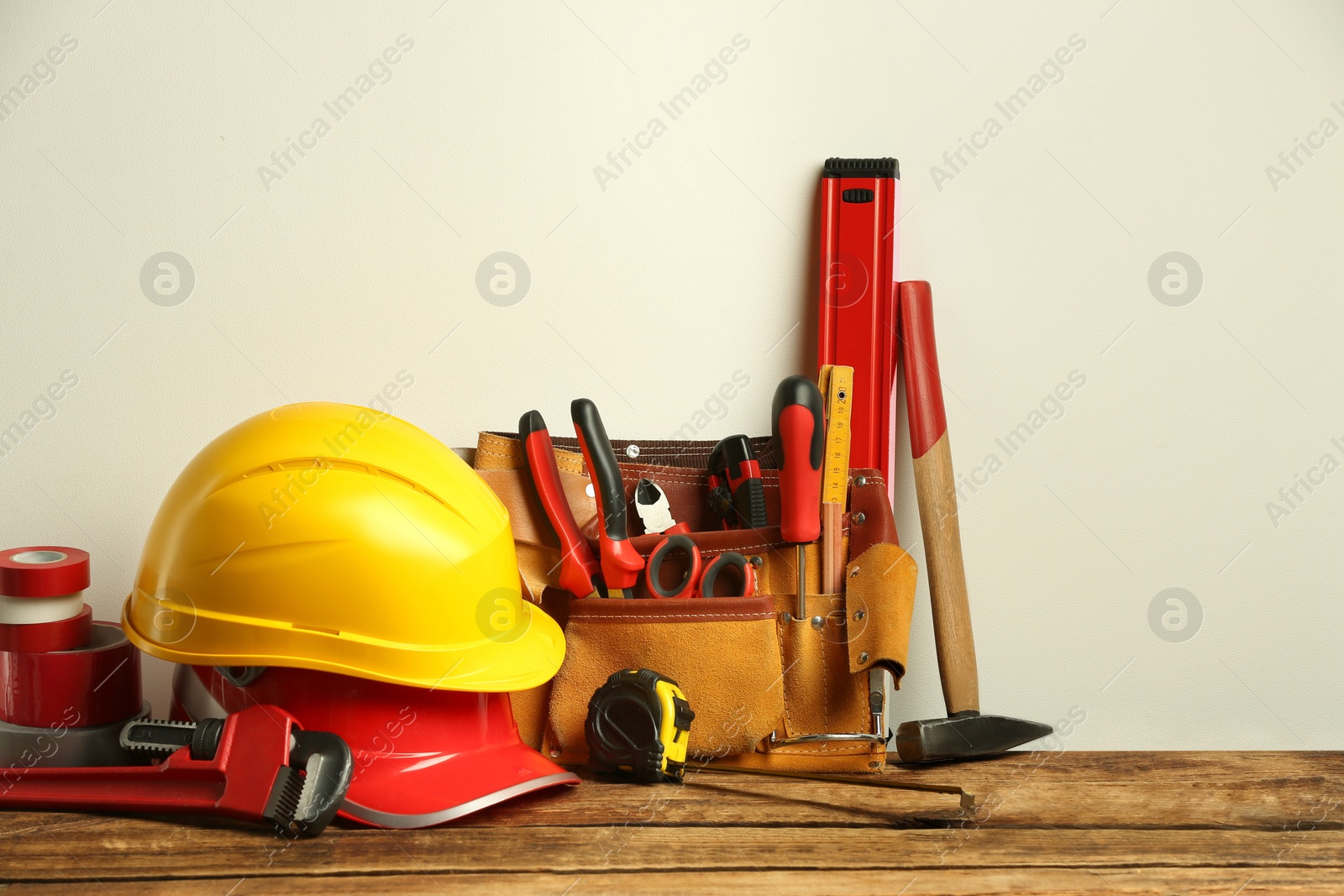 Photo of Leather belt with tools for repair and hard hats on wooden table