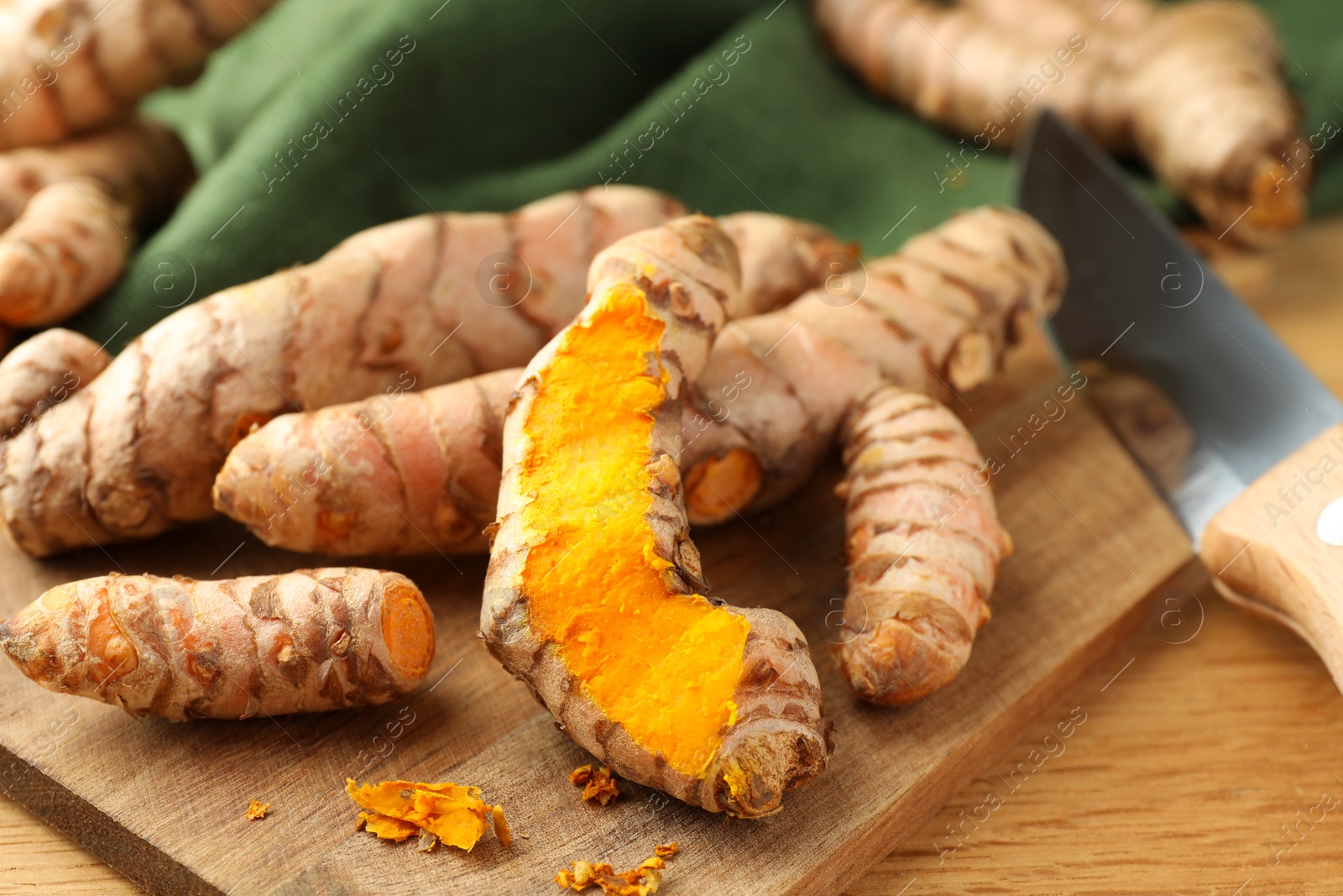 Photo of Many raw turmeric roots on wooden table, closeup