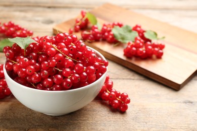 Photo of Delicious red currants on wooden table. Space for text