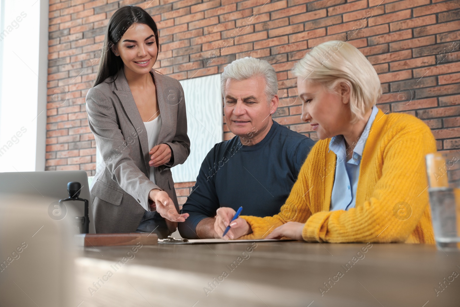 Photo of Female notary working with mature couple in office