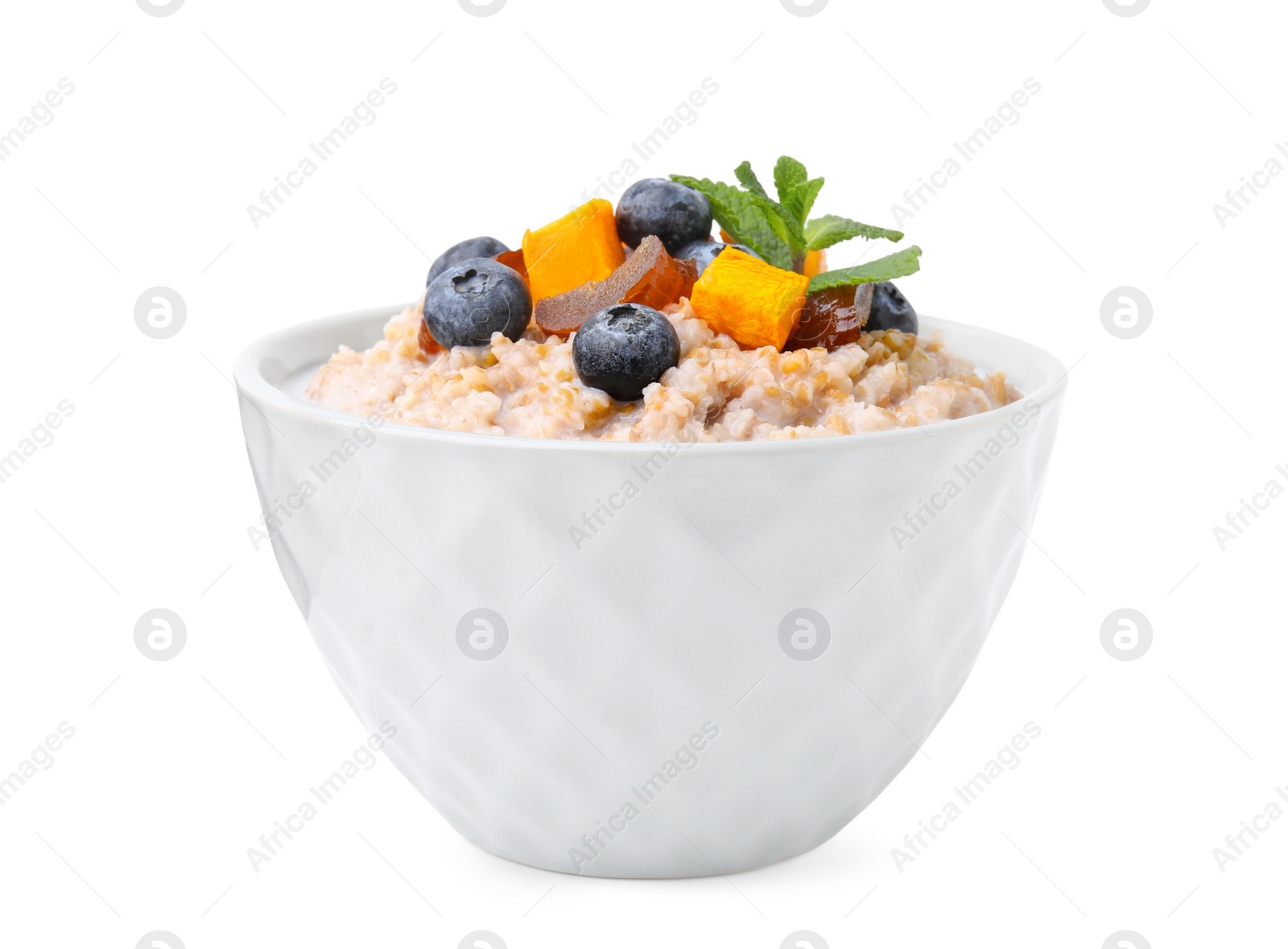 Photo of Tasty wheat porridge with milk, pumpkin, dates and blueberries in bowl isolated on white