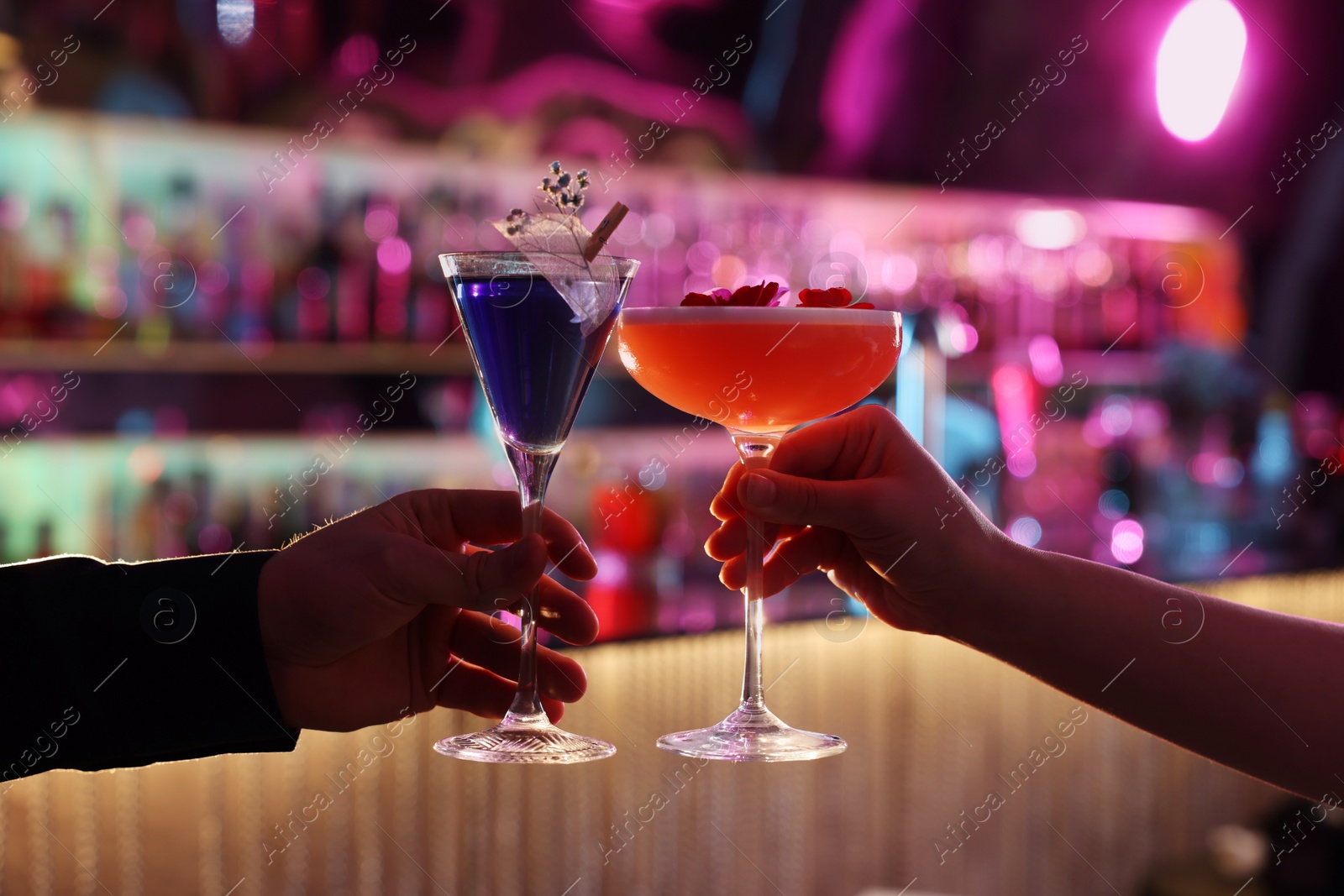 Photo of Man and woman clinking glasses with alcoholic cocktails in bar, closeup