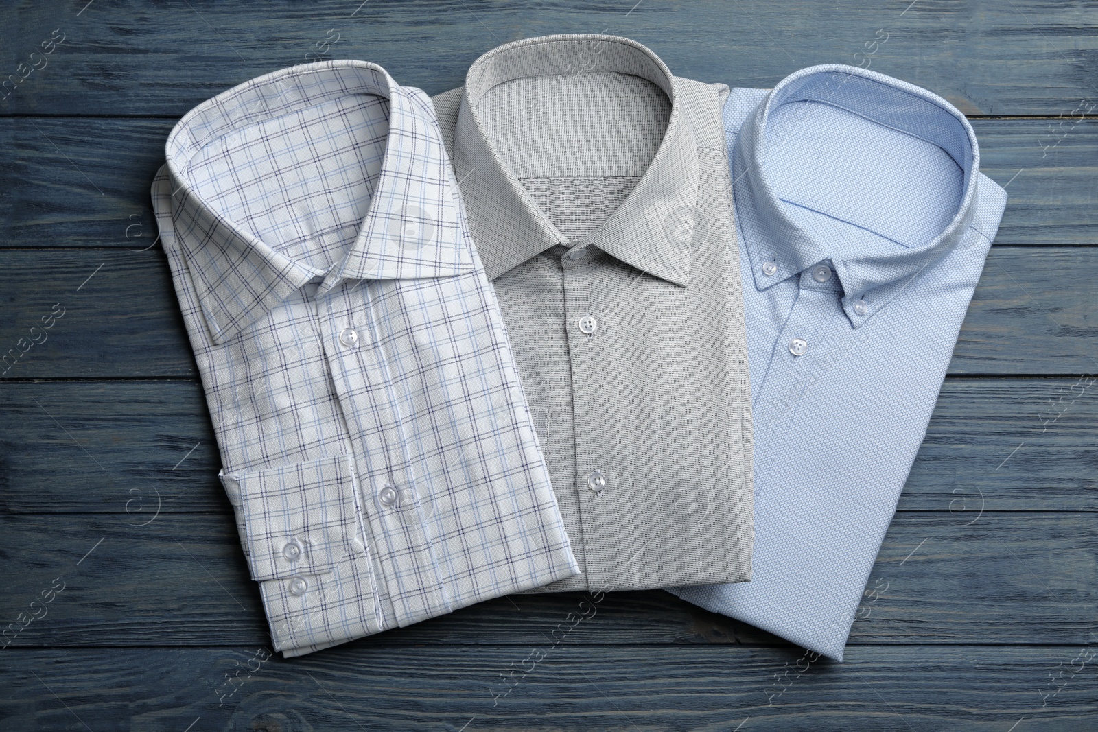 Photo of Stylish male shirts on blue wooden background, flat lay