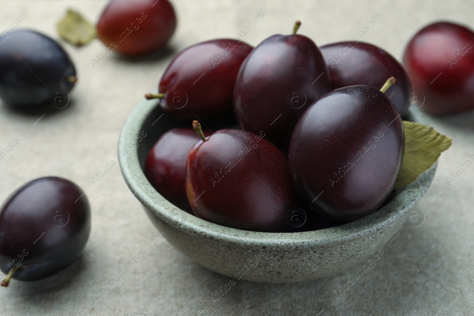 Photo of Many tasty ripe plums on light fabric, closeup