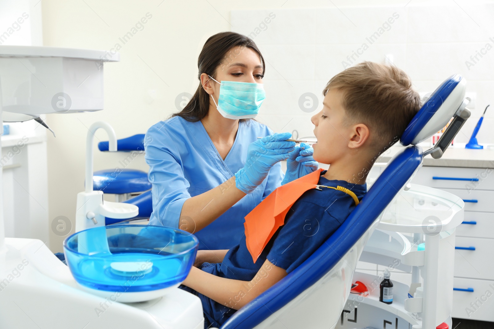 Photo of Professional dentist working with little boy in clinic