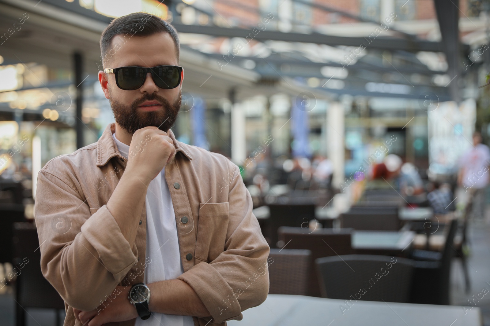 Photo of Portrait of handsome stylish man in sunglasses on city street. Space for text