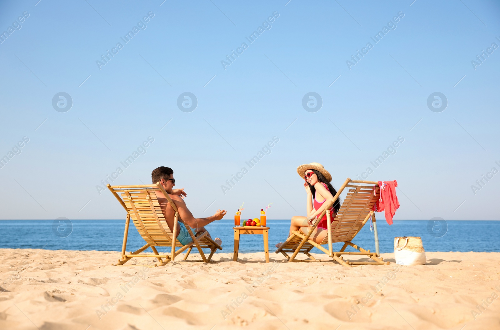 Photo of Couple resting on sunny beach at resort