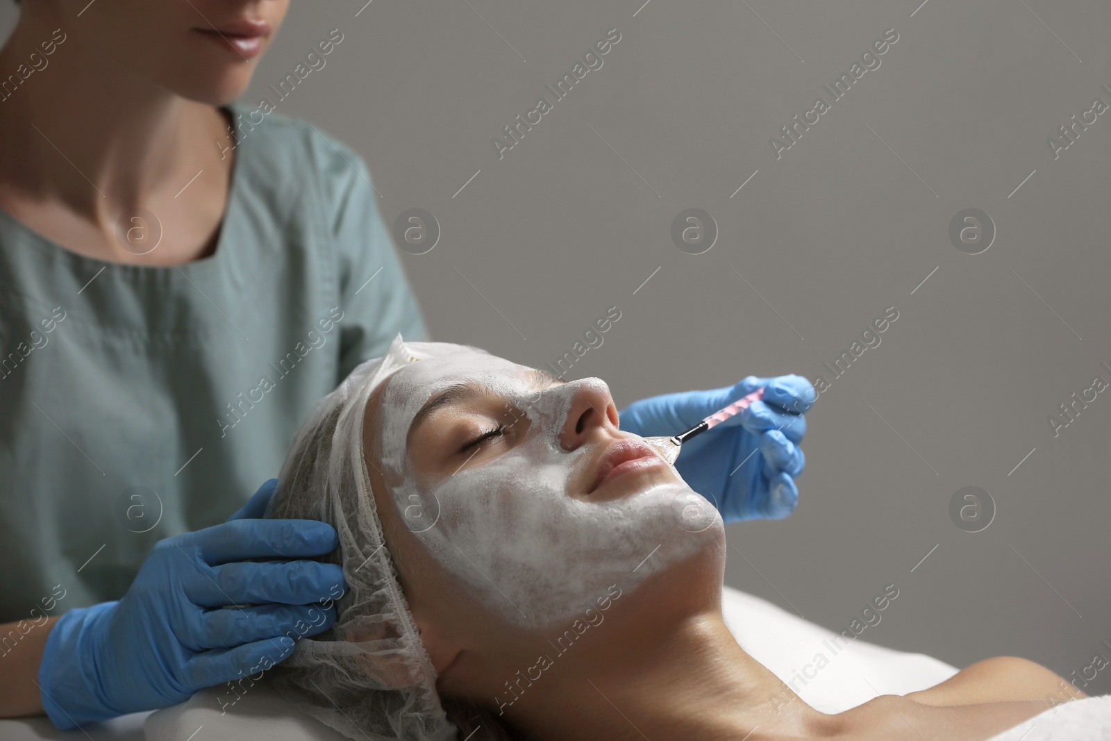 Photo of Cosmetologist applying mask on client's face in spa salon