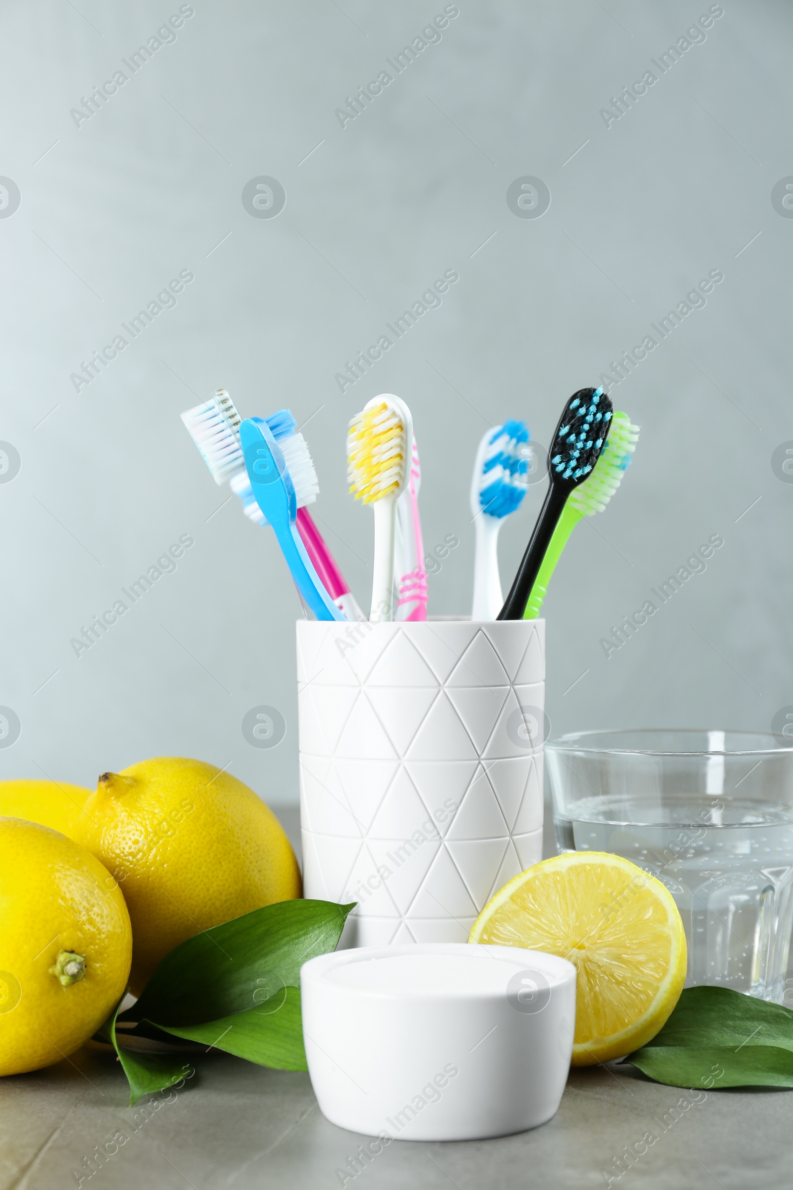 Photo of Toothbrushes, lemons and bowl of baking soda on grey table