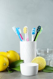 Toothbrushes, lemons and bowl of baking soda on grey table
