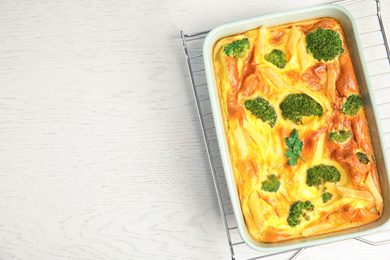 Photo of Tasty broccoli casserole in baking dish on cooling rack, top view. Space for text