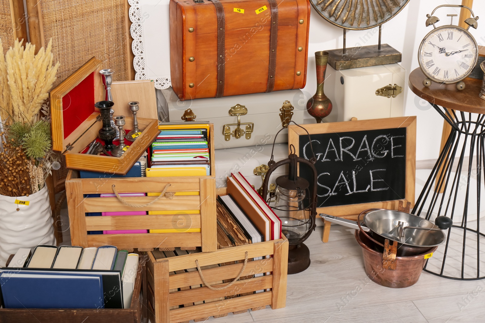 Photo of Sign Garage Sale written on blackboard near many different stuff indoors