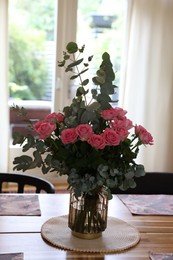 Beautiful bouquet of roses and napkins on wooden table indoors