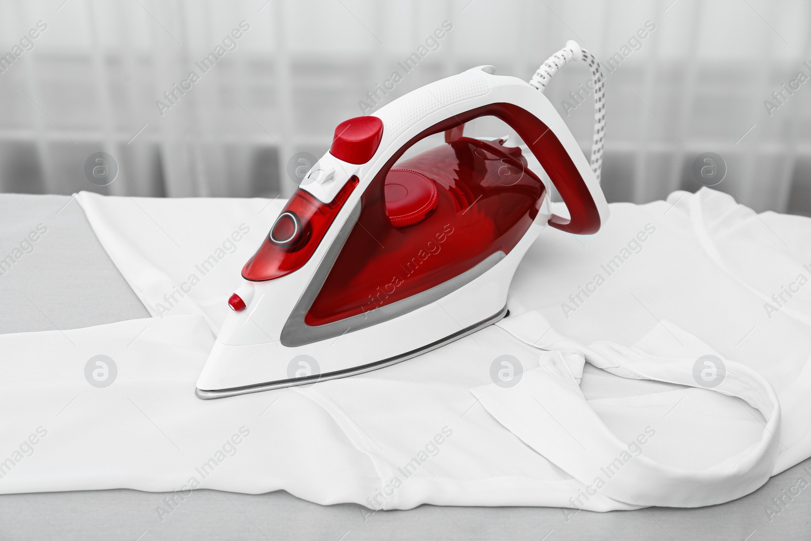 Photo of Modern iron and white clean shirt on board indoors