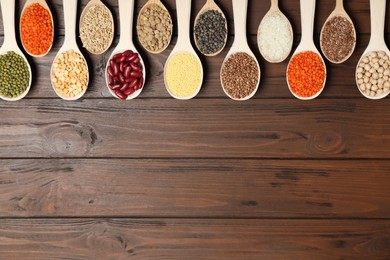 Photo of Flat lay composition with different types of legumes and cereals on wooden table, space for text. Organic grains